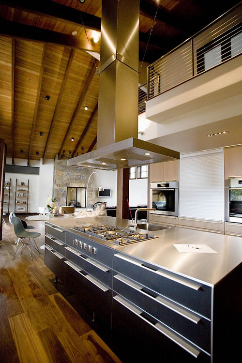 Modern inredning av ett mellanstort kök med öppen planlösning, med rostfria vitvaror, ljust trägolv, en köksö, en integrerad diskho, släta luckor, grå skåp, bänkskiva i rostfritt stål och beiget golv
