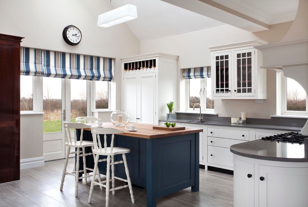 Стильный дизайн: кухня в классическом стиле с белыми фасадами, деревянной столешницей и островом - последний тренд