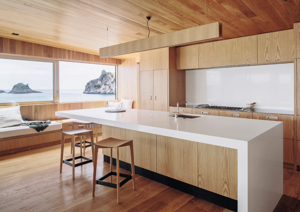 Zweizeilige Moderne Küche mit Unterbauwaschbecken, flächenbündigen Schrankfronten, hellbraunen Holzschränken, dunklem Holzboden, Kücheninsel, braunem Boden und weißer Arbeitsplatte