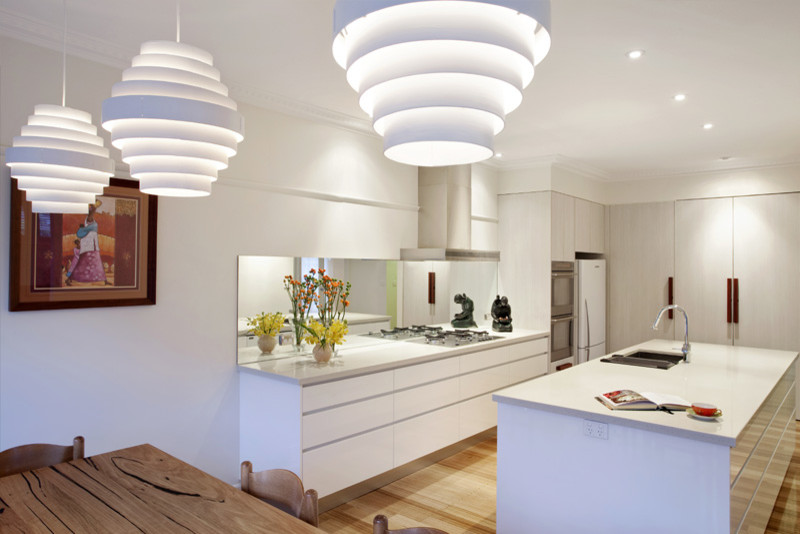 Cette image montre une grande cuisine design en L avec des portes de placard blanches, îlot et un plan de travail blanc.
