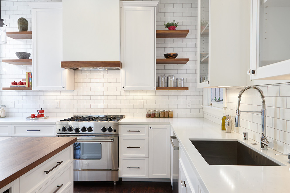 This is an example of a medium sized classic l-shaped kitchen/diner in San Francisco with a single-bowl sink, shaker cabinets, white cabinets, engineered stone countertops, white splashback, metro tiled splashback, stainless steel appliances, dark hardwood flooring and an island.