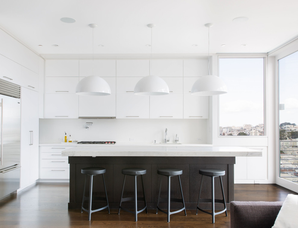 Immagine di una cucina minimal con lavello sottopiano, ante lisce, ante bianche, elettrodomestici in acciaio inossidabile, parquet scuro, pavimento marrone e top bianco