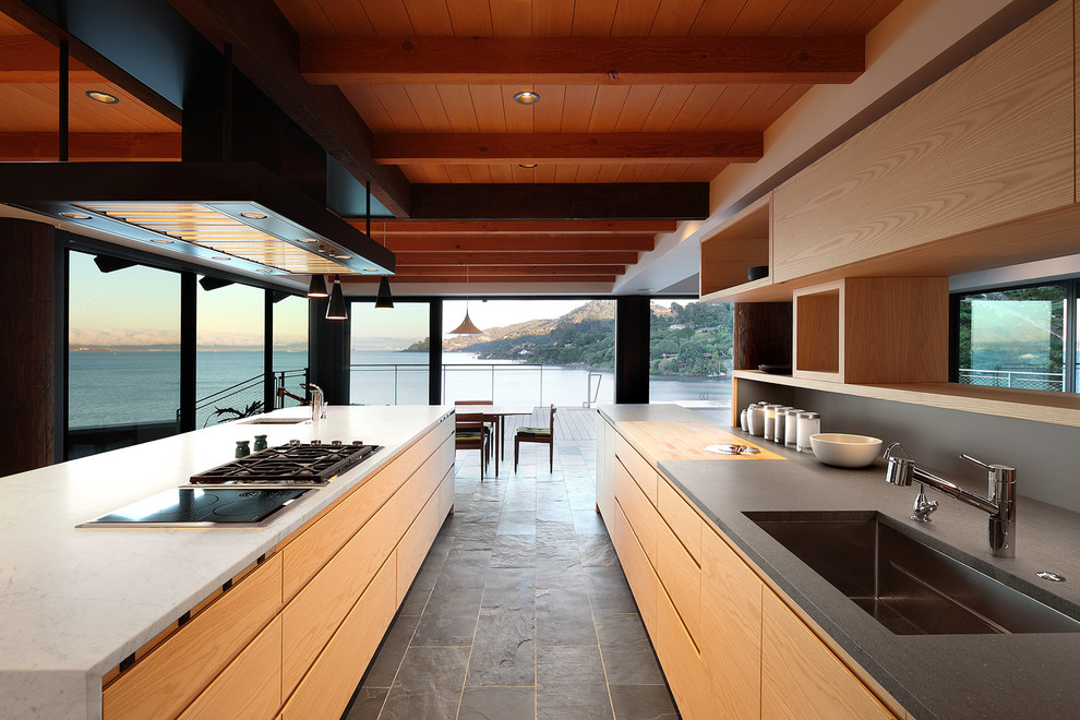 Esempio di una grande cucina minimal con lavello sottopiano, ante lisce, ante in legno chiaro, top in superficie solida, elettrodomestici in acciaio inossidabile, pavimento in ardesia, pavimento grigio e paraspruzzi grigio