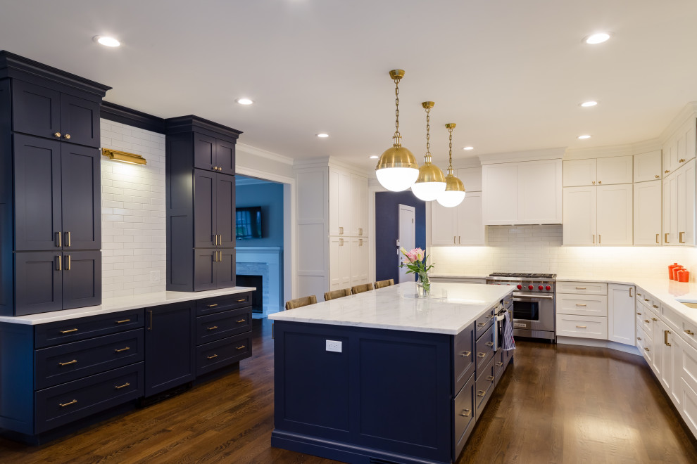 Inspiration for a large transitional l-shaped dark wood floor and brown floor eat-in kitchen remodel in New York with an undermount sink, flat-panel cabinets, white cabinets, marble countertops, white backsplash, porcelain backsplash, paneled appliances, an island and white countertops