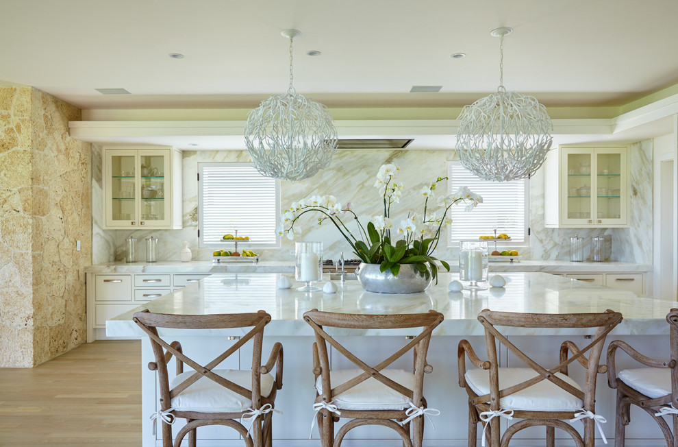 Immagine di una grande cucina tropicale con ante di vetro, ante bianche, top in marmo e parquet chiaro