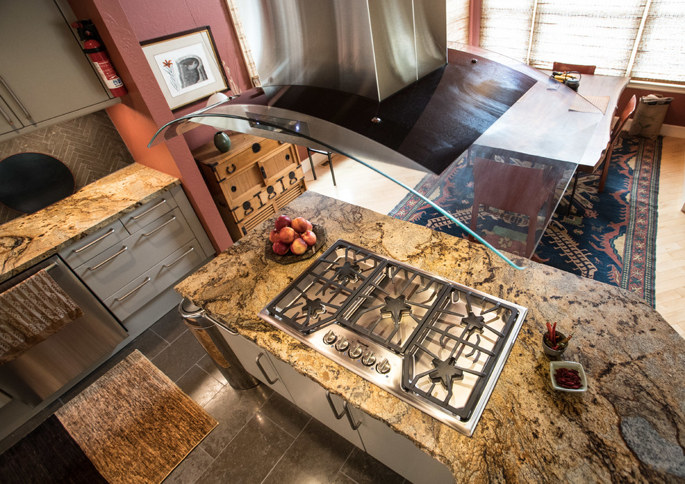 Inredning av ett modernt mellanstort kök, med släta luckor, grå skåp, granitbänkskiva, grått stänkskydd, rostfria vitvaror, en halv köksö, en enkel diskho, stänkskydd i stenkakel och kalkstensgolv