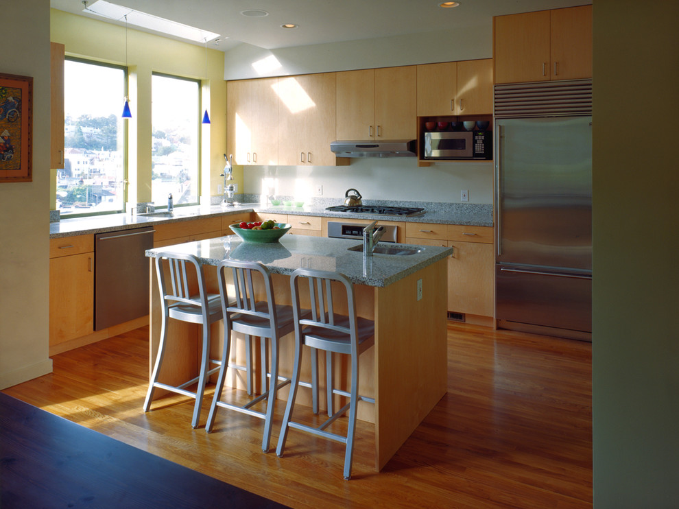 Свежая идея для дизайна: кухня в современном стиле с плоскими фасадами, светлыми деревянными фасадами и техникой из нержавеющей стали - отличное фото интерьера