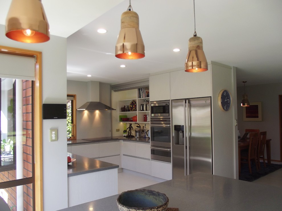 Foto på ett mellanstort funkis u-kök, med grå skåp, bänkskiva i koppar, grått stänkskydd, rostfria vitvaror, klinkergolv i porslin och en köksö
