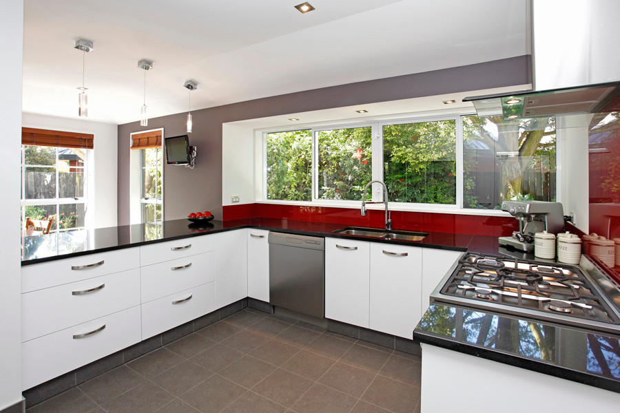 Inspiration for a mid-sized contemporary u-shaped ceramic tile eat-in kitchen remodel in Christchurch with an undermount sink, quartz countertops, red backsplash, glass sheet backsplash and stainless steel appliances