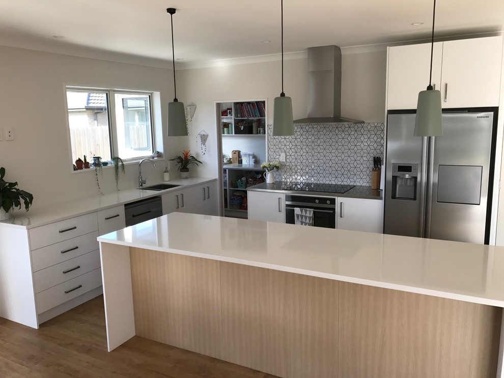 Bild på ett stort funkis kök, med en undermonterad diskho, vita skåp, bänkskiva i kvarts, flerfärgad stänkskydd, stänkskydd i mosaik, rostfria vitvaror, vinylgolv och en köksö