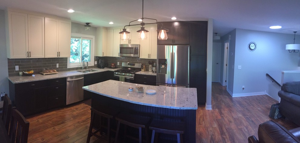 Inspiration for a mid-sized transitional l-shaped laminate floor and brown floor eat-in kitchen remodel in Minneapolis with a drop-in sink, shaker cabinets, white cabinets, granite countertops, gray backsplash, glass tile backsplash, stainless steel appliances, an island and white countertops