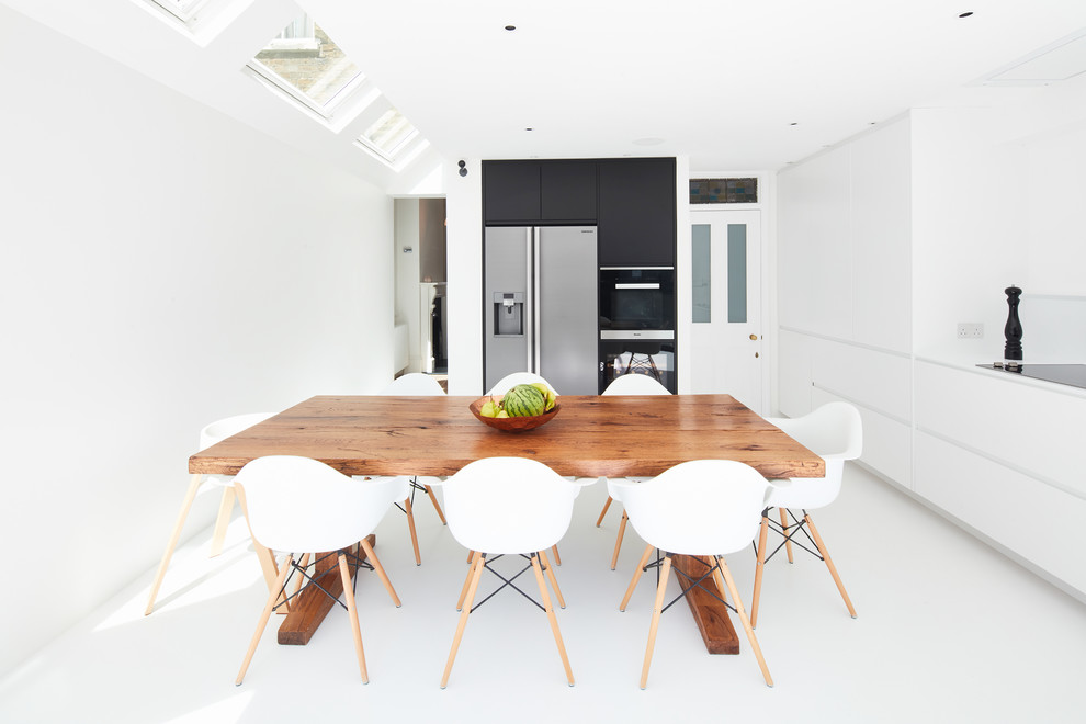 Design ideas for a medium sized contemporary l-shaped kitchen/diner in London with a built-in sink, flat-panel cabinets, white cabinets, white splashback, black appliances, no island and white floors.