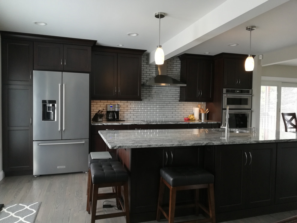 Foto på ett mellanstort funkis vit linjärt kök och matrum, med en undermonterad diskho, skåp i shakerstil, skåp i mörkt trä, granitbänkskiva, stänkskydd med metallisk yta, stänkskydd i tunnelbanekakel, rostfria vitvaror, en köksö och grått golv