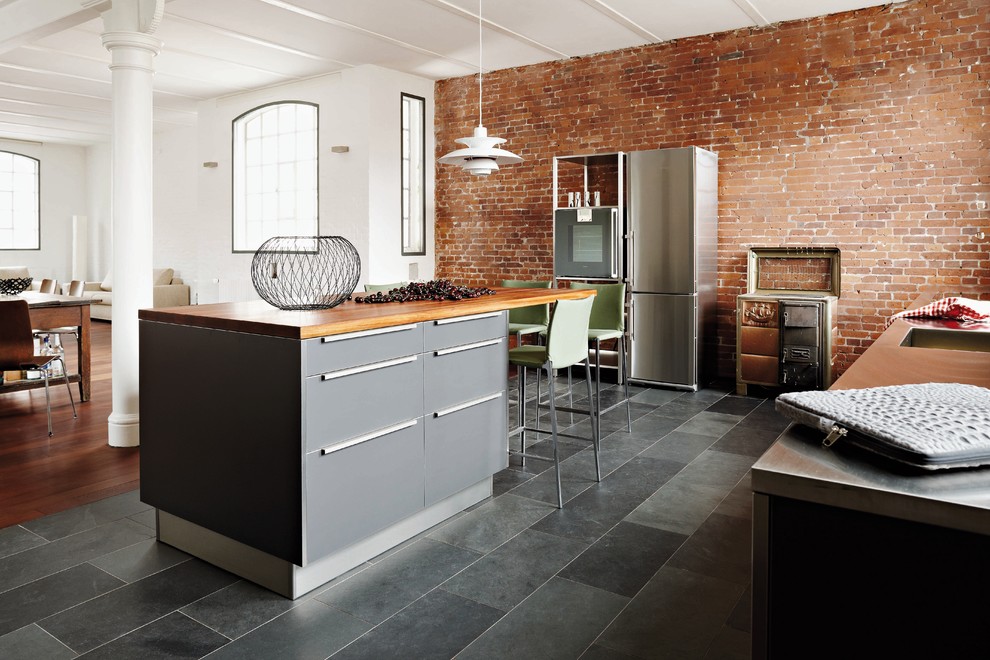 Immagine di una cucina industriale di medie dimensioni con lavello integrato, ante lisce, ante grigie, top in legno e elettrodomestici in acciaio inossidabile