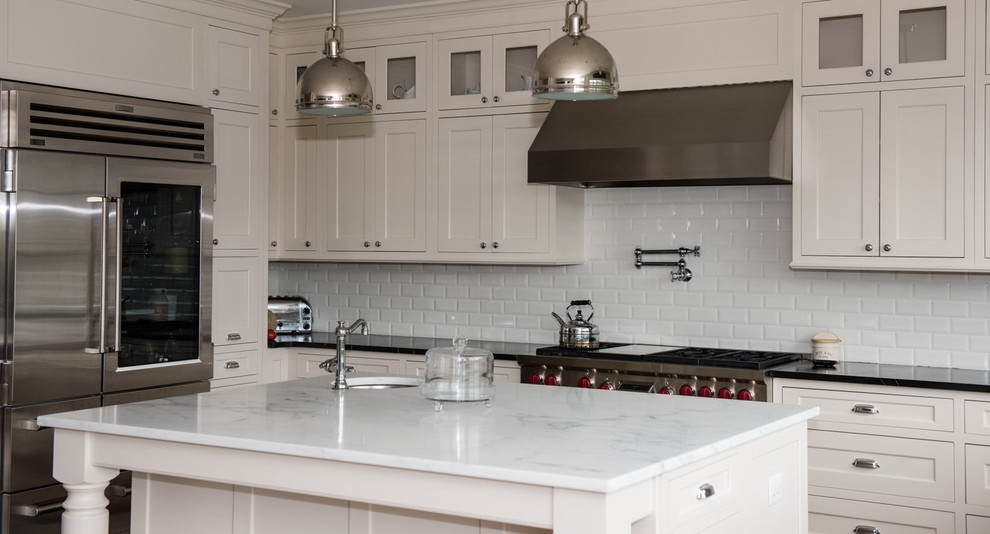 Bild på ett stort amerikanskt kök, med en undermonterad diskho, luckor med profilerade fronter, vita skåp, marmorbänkskiva, vitt stänkskydd, stänkskydd i keramik, rostfria vitvaror, mörkt trägolv och en köksö