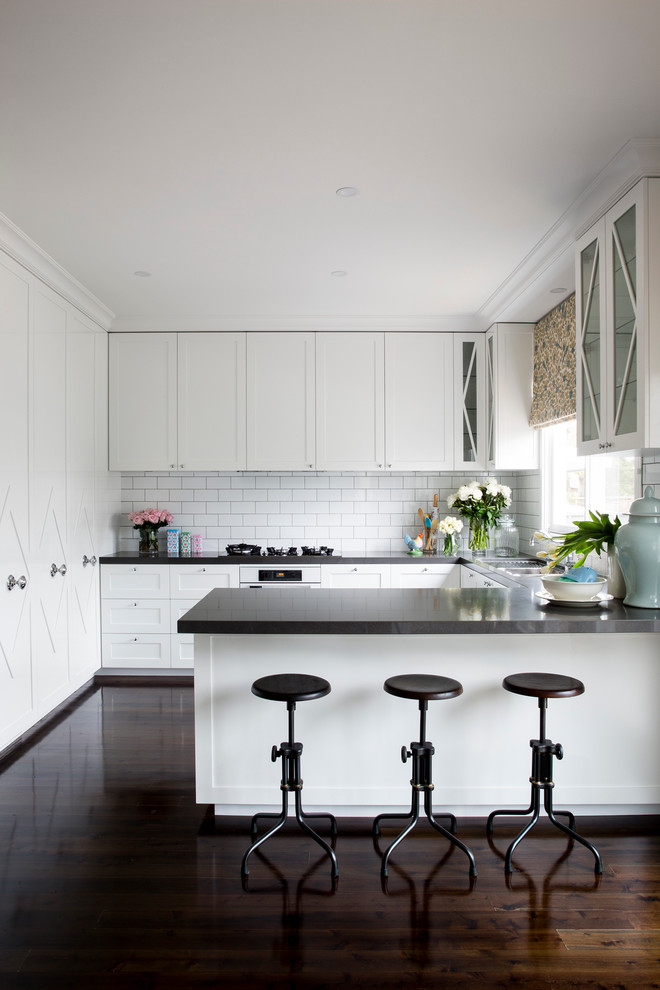 Transitional dark wood floor kitchen photo in Sydney with shaker cabinets, white cabinets, white backsplash and a peninsula