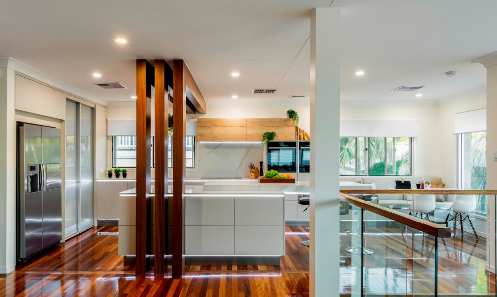 Large trendy l-shaped medium tone wood floor and multicolored floor eat-in kitchen photo in Brisbane with an undermount sink, flat-panel cabinets, beige cabinets, quartz countertops, white backsplash, stone slab backsplash, black appliances, an island and yellow countertops