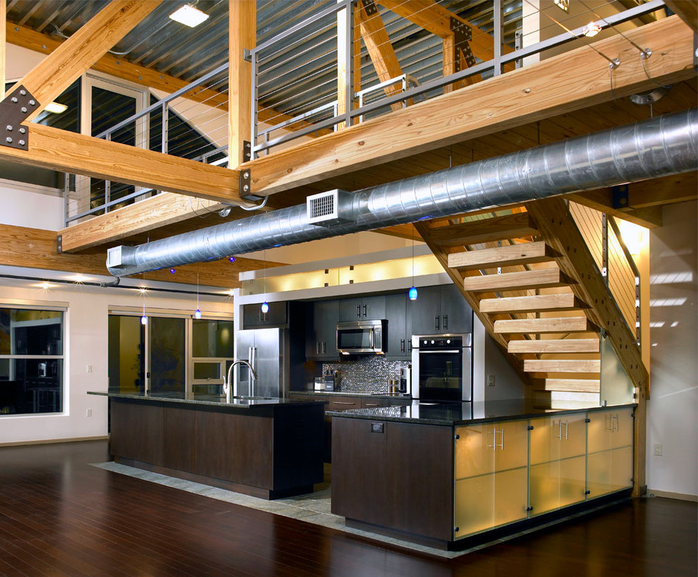 Exempel på ett mellanstort industriellt kök, med en undermonterad diskho, släta luckor, skåp i mörkt trä, rostfria vitvaror och en köksö