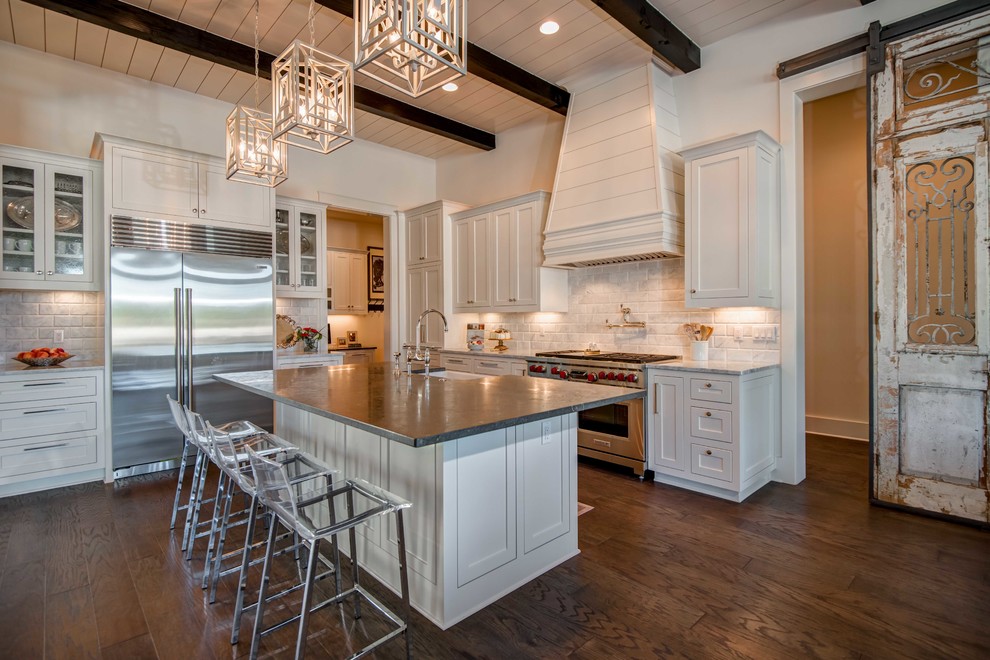 Inspiration for a transitional l-shaped dark wood floor kitchen remodel in Austin with shaker cabinets, white cabinets, white backsplash, stainless steel appliances and an island