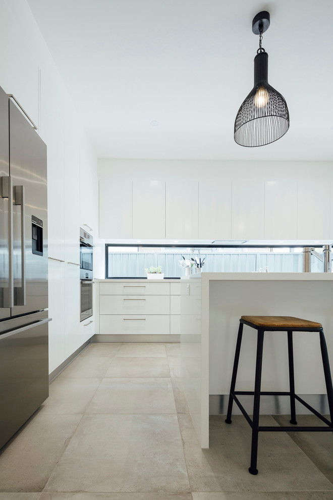 Foto på ett funkis kök, med en undermonterad diskho, släta luckor, vita skåp, granitbänkskiva, fönster som stänkskydd, rostfria vitvaror, skiffergolv och en köksö
