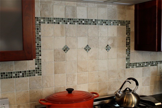 Inredning av ett klassiskt avskilt, mellanstort u-kök, med en undermonterad diskho, luckor med infälld panel, röda skåp, granitbänkskiva, grönt stänkskydd, stänkskydd i mosaik, rostfria vitvaror, klinkergolv i keramik och en köksö