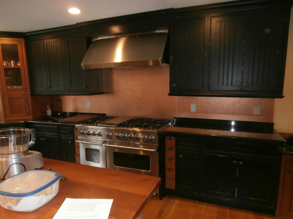 Foto på ett stort vintage linjärt kök och matrum, med luckor med infälld panel, svarta skåp, stänkskydd i metallkakel, rostfria vitvaror och en köksö