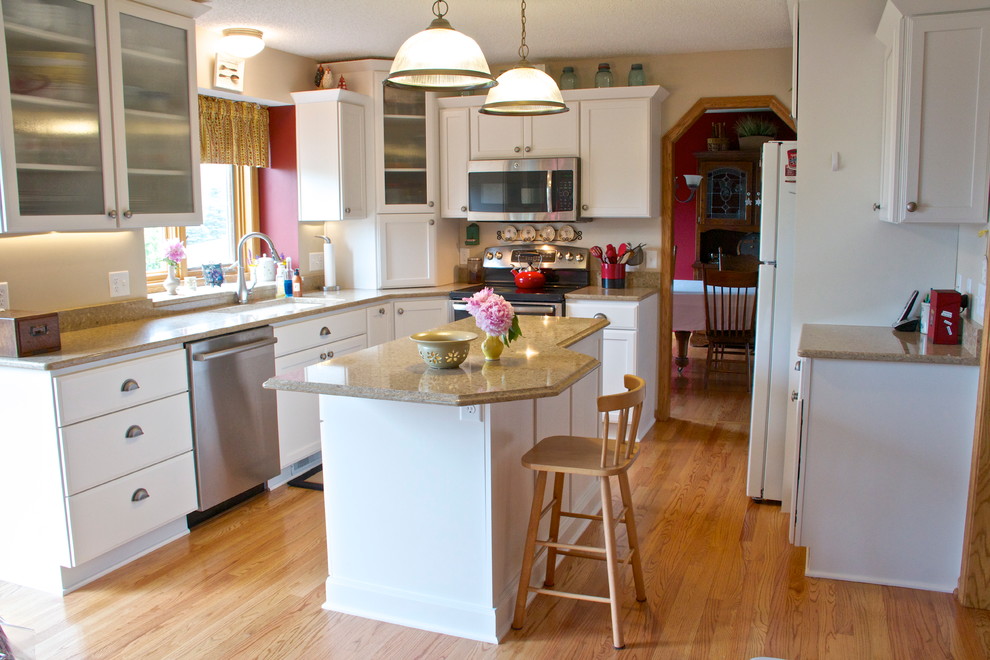 Foto på ett mellanstort vintage kök, med en undermonterad diskho, släta luckor, vita skåp, bänkskiva i kvartsit, rostfria vitvaror, ljust trägolv och en köksö