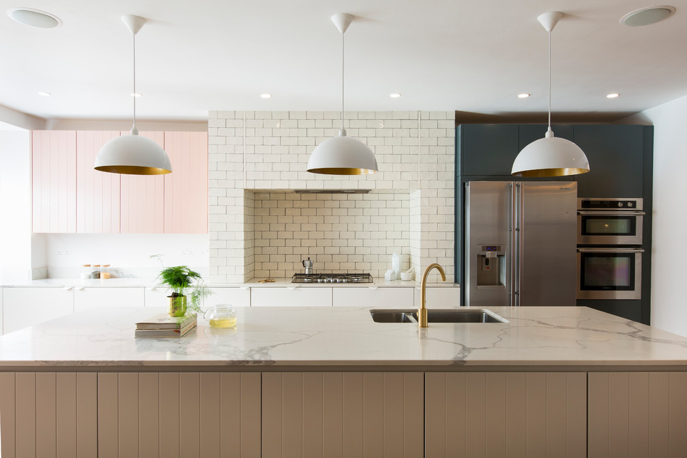 Design ideas for an expansive contemporary grey and pink single-wall open plan kitchen in London with a double-bowl sink, beaded cabinets, white cabinets, marble worktops, white splashback, metro tiled splashback, stainless steel appliances, an island, white worktops, medium hardwood flooring, brown floors and a chimney breast.