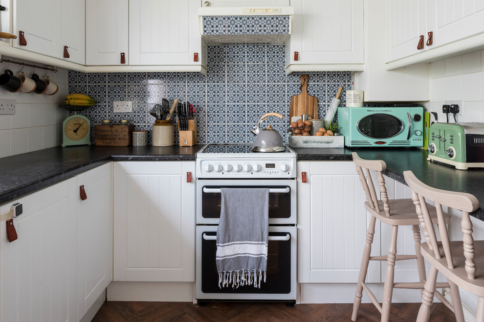 Kleine Shabby-Look Küche in U-Form mit Kassettenfronten, weißen Schränken, bunter Rückwand, Halbinsel und braunem Boden in London