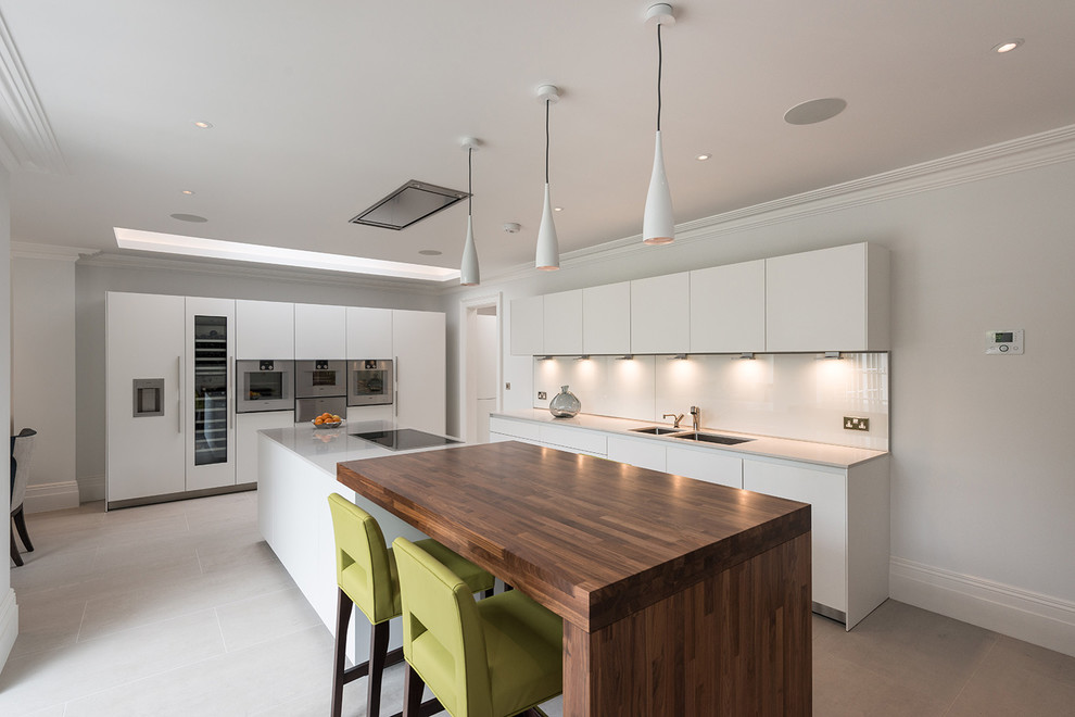 Design ideas for a large contemporary u-shaped kitchen/diner in London with a double-bowl sink, flat-panel cabinets, white cabinets, composite countertops, white splashback, glass sheet splashback, stainless steel appliances, ceramic flooring and an island.