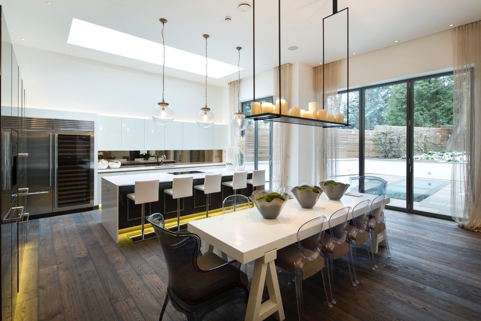 Foto på ett stort funkis kök och matrum, med en undermonterad diskho, släta luckor, vita skåp, stänkskydd med metallisk yta, rostfria vitvaror, ljust trägolv, en halv köksö och brunt golv