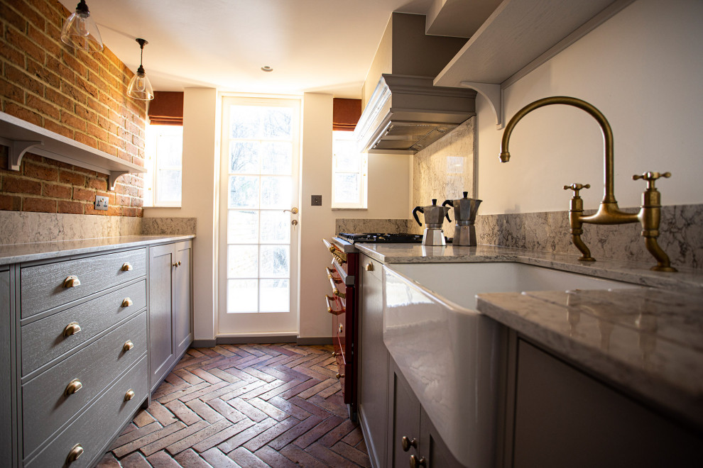 This is an example of a small traditional galley enclosed kitchen in London with a belfast sink and terracotta flooring.