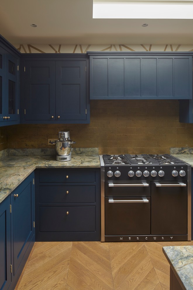 Offene, Große Klassische Küche in U-Form mit integriertem Waschbecken, Kassettenfronten, blauen Schränken, Granit-Arbeitsplatte, Rückwand aus Steinfliesen, Küchengeräten aus Edelstahl, braunem Holzboden, Kücheninsel und braunem Boden in London