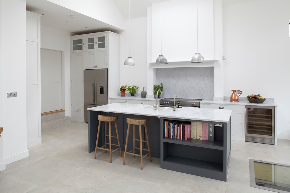 This is an example of a medium sized classic open plan kitchen in London with a belfast sink, shaker cabinets, grey cabinets, marble worktops, marble splashback, stainless steel appliances, porcelain flooring and an island.