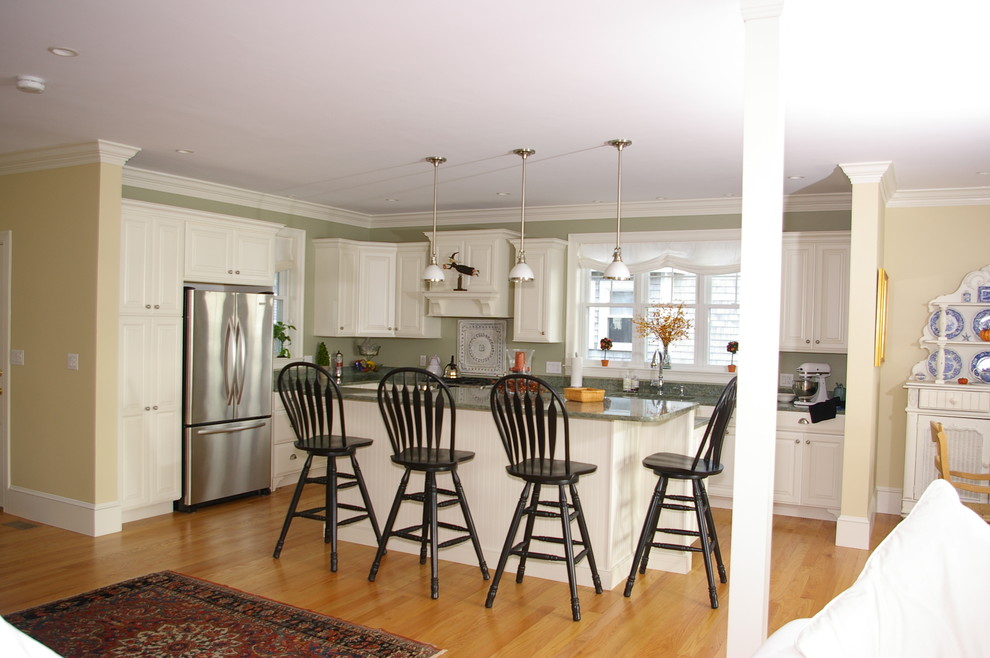 Example of a mid-sized classic l-shaped light wood floor and brown floor eat-in kitchen design in Boston with raised-panel cabinets, white cabinets, granite countertops, green backsplash, stainless steel appliances, a farmhouse sink, matchstick tile backsplash and an island