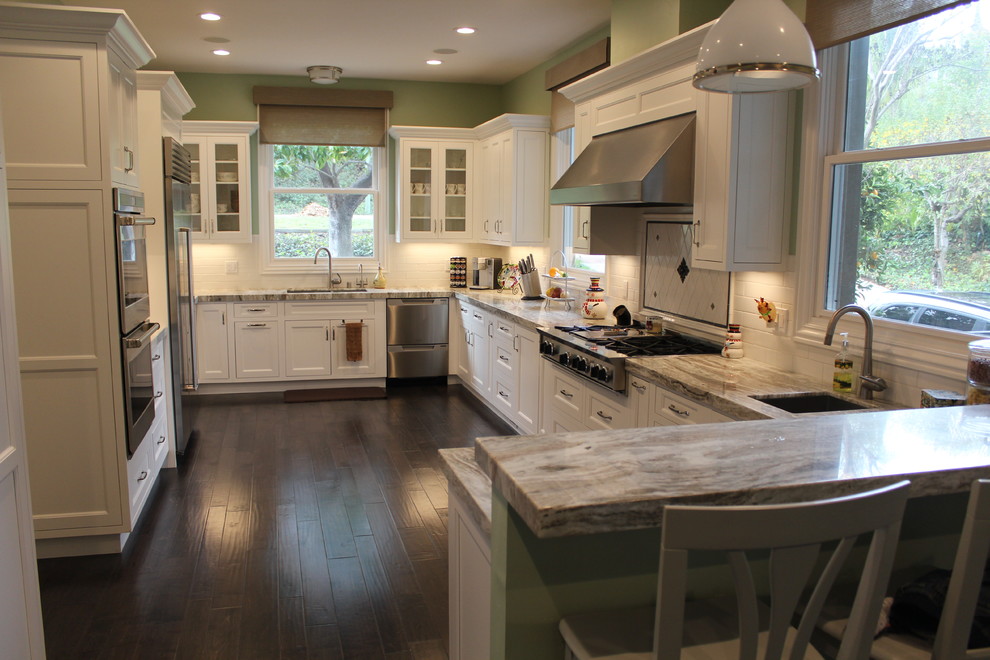 Example of a mid-sized classic u-shaped dark wood floor enclosed kitchen design in San Francisco with an undermount sink, beaded inset cabinets, white cabinets, quartzite countertops, white backsplash, ceramic backsplash and stainless steel appliances