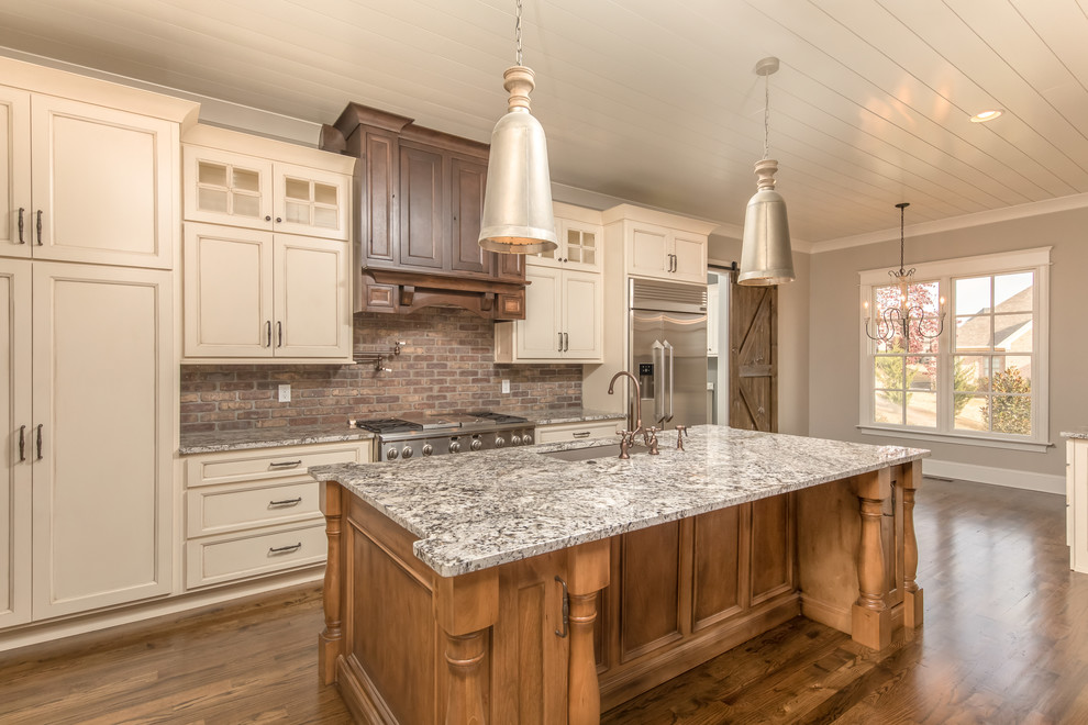 Eat-in kitchen - mid-sized craftsman single-wall dark wood floor eat-in kitchen idea in Other with an undermount sink, recessed-panel cabinets, granite countertops, red backsplash, brick backsplash, stainless steel appliances, an island and beige cabinets
