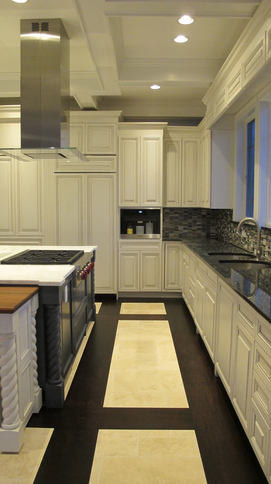 Bild på ett stort maritimt kök, med en undermonterad diskho, luckor med upphöjd panel, beige skåp, marmorbänkskiva, blått stänkskydd, stänkskydd i glaskakel, rostfria vitvaror, travertin golv och flera köksöar