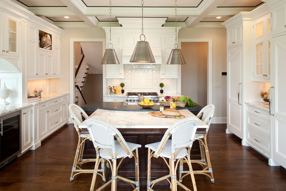 Example of a large classic u-shaped dark wood floor eat-in kitchen design in Minneapolis with a farmhouse sink, recessed-panel cabinets, white cabinets, marble countertops, white backsplash, subway tile backsplash, stainless steel appliances and an island