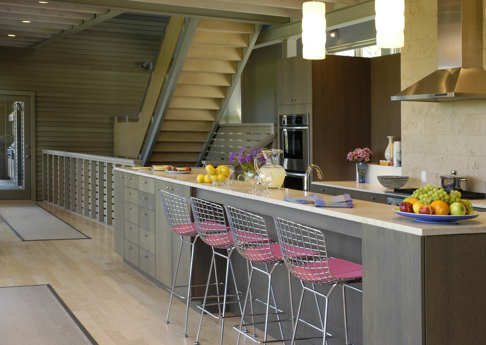 Inspiration for a cottage kitchen remodel in New York with stainless steel appliances, stone tile backsplash, beige backsplash, dark wood cabinets, flat-panel cabinets and beige countertops