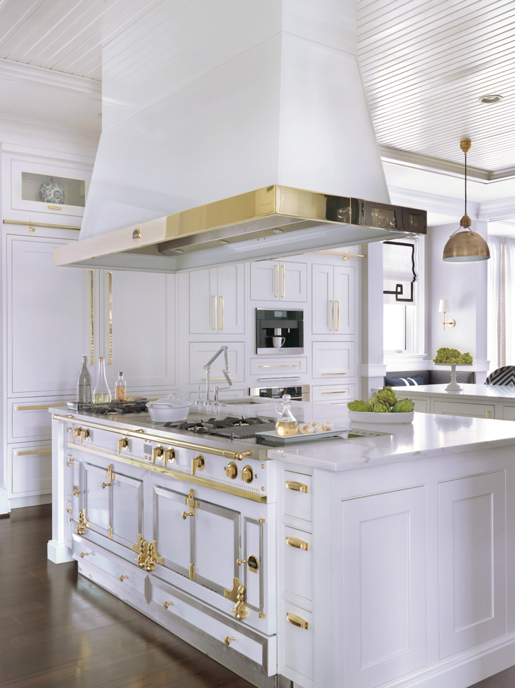 Klassisk inredning av ett mycket stort kök, med en undermonterad diskho, skåp i shakerstil, vita skåp, rostfria vitvaror, mörkt trägolv, flera köksöar och brunt golv