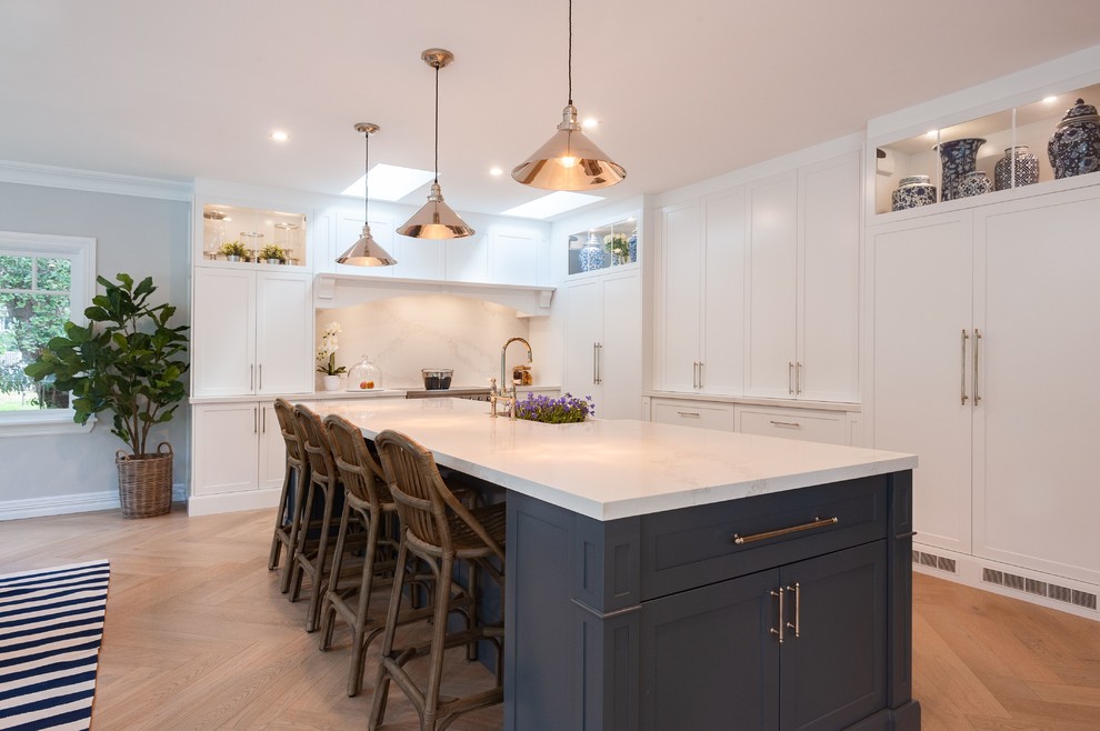 Inspiration for a huge timeless l-shaped light wood floor eat-in kitchen remodel in Wollongong with a farmhouse sink, shaker cabinets, white cabinets, quartz countertops, white backsplash, marble backsplash, stainless steel appliances, an island and white countertops