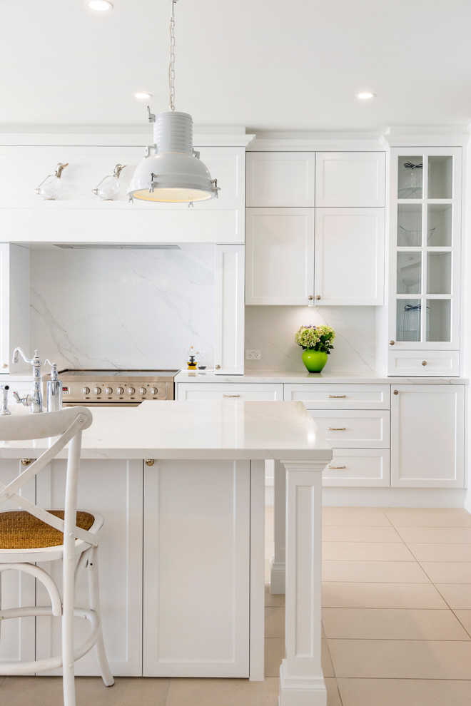 Maritim inredning av ett stort vit vitt kök, med en rustik diskho, skåp i shakerstil, vita skåp, marmorbänkskiva, vitt stänkskydd, stänkskydd i marmor, rostfria vitvaror, klinkergolv i keramik, en köksö och beiget golv