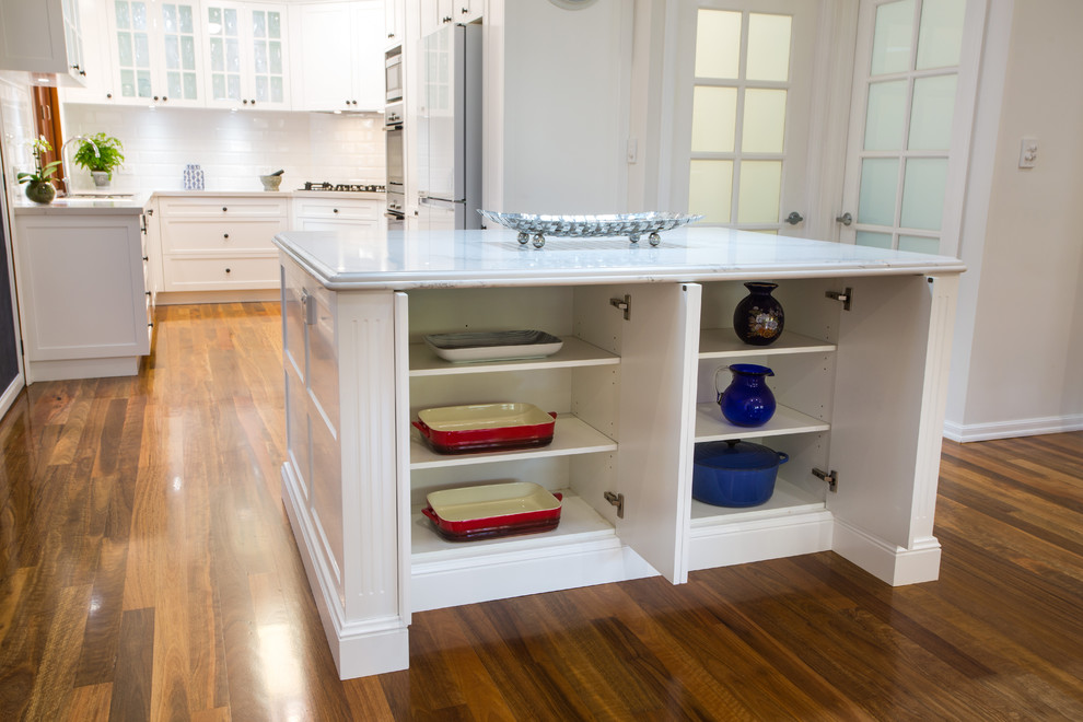 Inspiration for a large timeless u-shaped medium tone wood floor and brown floor open concept kitchen remodel in Brisbane with a double-bowl sink, shaker cabinets, white cabinets, quartz countertops, white backsplash, subway tile backsplash, black appliances and an island
