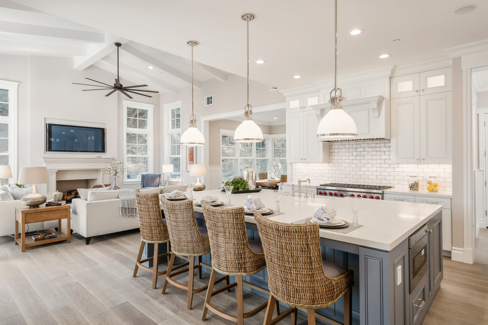 Example of a classic l-shaped medium tone wood floor kitchen design in San Francisco with a farmhouse sink, recessed-panel cabinets, white cabinets, quartz countertops, white backsplash, subway tile backsplash, stainless steel appliances and an island