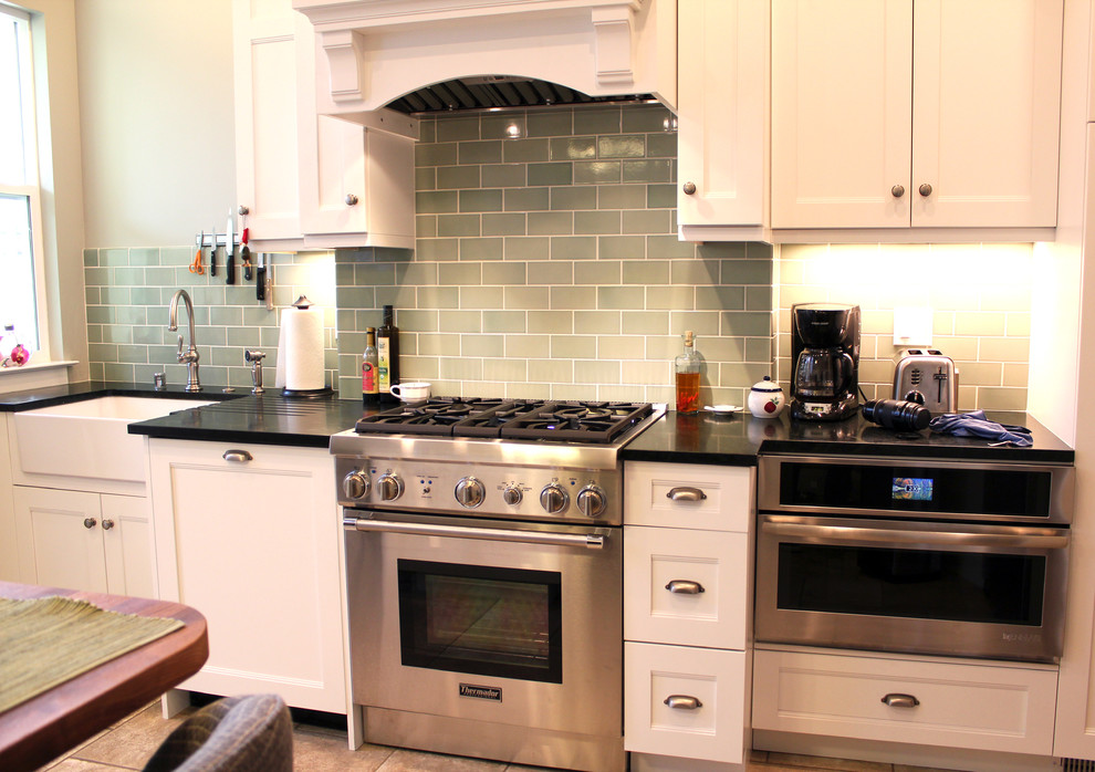 Exempel på ett klassiskt kök och matrum, med en rustik diskho, skåp i shakerstil, vita skåp, bänkskiva i täljsten, grönt stänkskydd, stänkskydd i keramik, rostfria vitvaror, klinkergolv i porslin och beiget golv