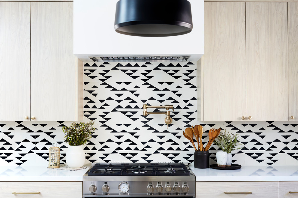 Example of a large trendy u-shaped concrete floor and gray floor open concept kitchen design in Los Angeles with an undermount sink, flat-panel cabinets, light wood cabinets, solid surface countertops, multicolored backsplash, cement tile backsplash, stainless steel appliances, an island and white countertops