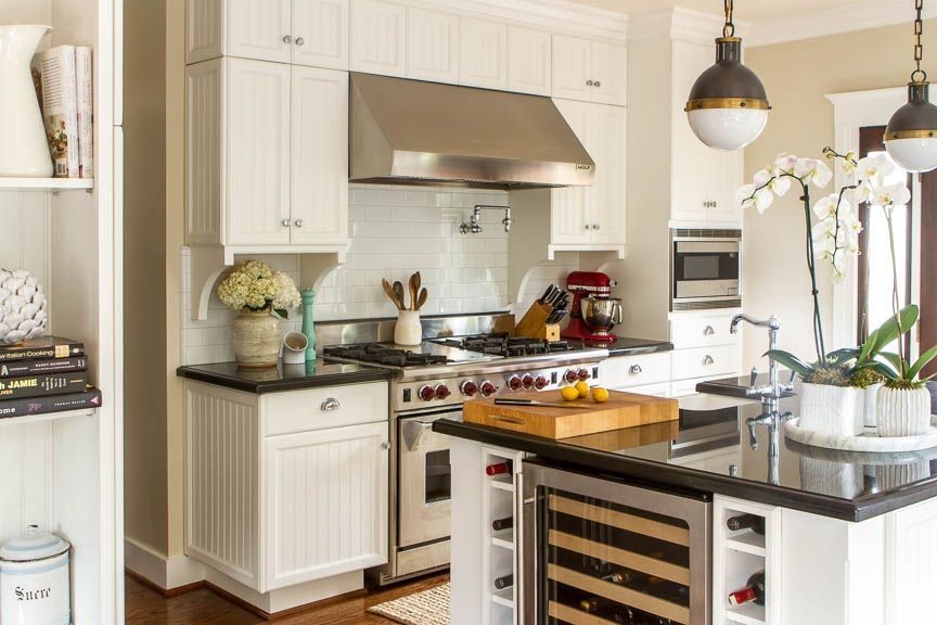 Example of a large eclectic dark wood floor eat-in kitchen design in New York with a farmhouse sink, beaded inset cabinets, white cabinets, granite countertops, white backsplash, subway tile backsplash, stainless steel appliances and an island