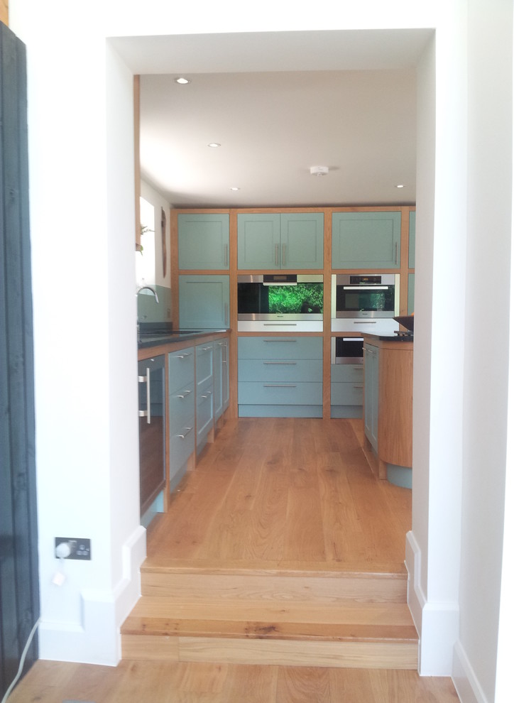 Photo of a large classic u-shaped kitchen in Oxfordshire with shaker cabinets, granite worktops, glass sheet splashback and an island.