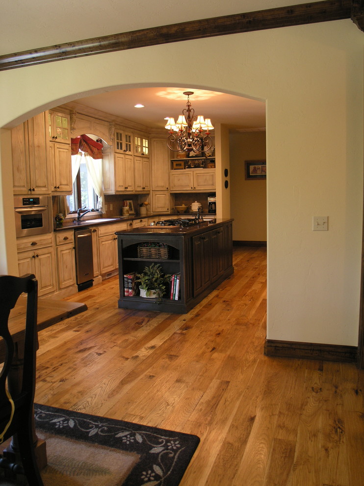 Example of a mid-sized classic u-shaped medium tone wood floor eat-in kitchen design in Oklahoma City with an undermount sink, raised-panel cabinets, light wood cabinets, granite countertops, beige backsplash, stainless steel appliances and an island
